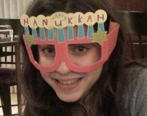 Mari Cohen at 17 years of age wearing menorah themed party glasses on her face
